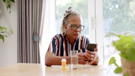 A-senior-African-American-woman-wearing-glasses-is-looking-at-smartphone