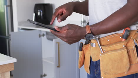 African-American-handyman-is-browsing-a-tablet-in-a-kitchen