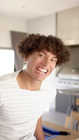 Vertical-video:-A-young-biracial-man-is-laughing-in-kitchen