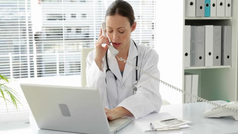 Doctor-talking-on-the-phone-at-her-desk