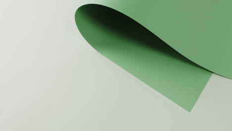 Close-up-of-green-rolled-piece-of-paper-on-white-background-with-copy-space-in-slow-motion
