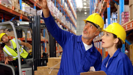 Warehouse-worker-showing-something-to-colleague