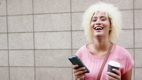 Una-Mujer-Joven-Con-Una-Sonrisa-Brillante-Sostiene-Un-Teléfono-Inteligente-En-París,-Copia-Espacio