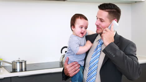 Father-holding-his-baby-son-before-work-and-talking-on-phone