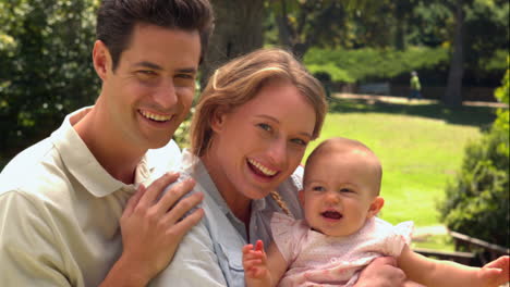 Parents-holding-their-baby-daughter-in-the-park