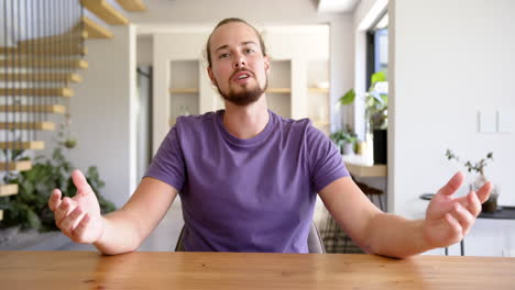 A-young-Caucasian-man-gestures-while-speaking-on-a-video-call-at-home