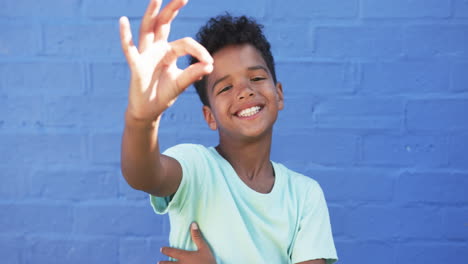 En-Un-Ambiente-Escolar,-Un-Joven-Afroamericano-Sonríe-Contra-Un-Fondo-Azul