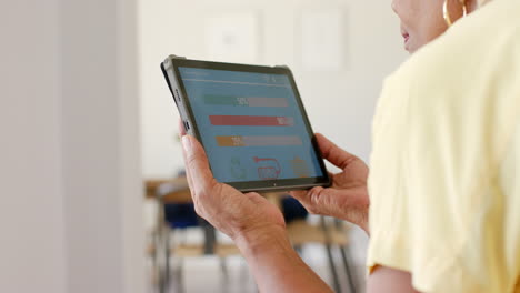 A-senior-African-American-woman-is-checking-home-energy-usage-on-tablet