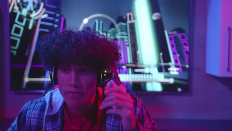 Biracial-man-chats-on-headset-amid-neon-lights,-copy-space
