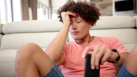 A-young-biracial-upset-and-stressed-man-looks-tired,-holding-a-remote