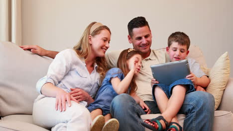 Happy-family-sitting-on-couch-using-tablet-pc