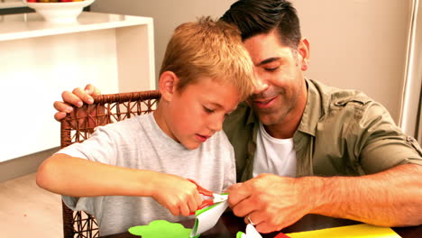 Father-and-son-making-paper-shapes-together-at-the-table