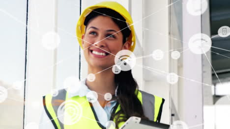 Animation-of-network-of-communication-icons-over-happy-biracial-female-architect-in-hard-hat