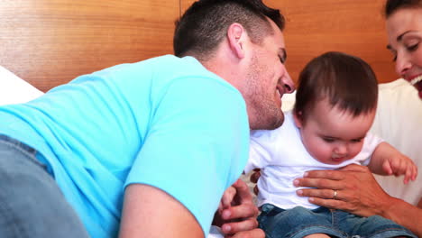 Happy-parents-kissing-their-baby-son-on-bed