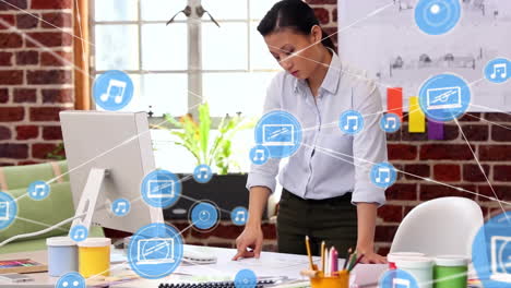 Animation-of-network-of-connections-with-icons-over-asian-businesswoman-using-computer