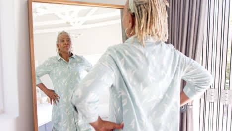 A-senior-African-American-woman-with-gray-hair-is-looking-at-herself-in-mirror