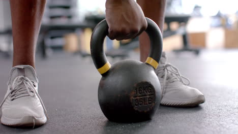 Nahaufnahme-Einer-16-Kg-Schweren-Kettlebell,-Die-Von-Einem-Afroamerikaner-In-Einem-Fitnessstudio-Angehoben-Wird