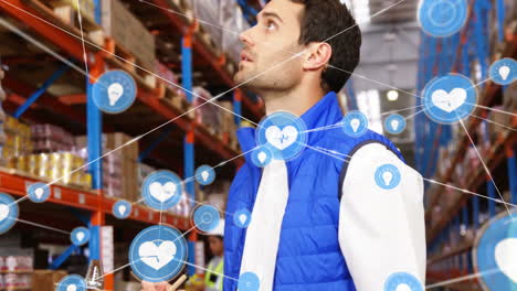 Animation-of-network-of-connections-with-heart-icons-over-caucasian-man-working-in-warehouse