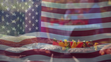 Animation-of-american-flag-over-food-on-barbecue-and-diverse-friends-celebrating-outdoors