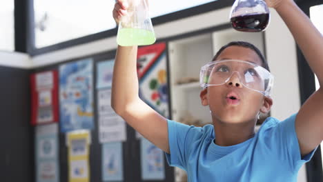 In-school,-in-a-classroom,-a-young-Asian-student-examines-chemical-reactions