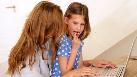 Little-girl-using-laptop-with-her-mother-at-the-table