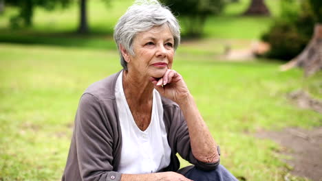 Upset-senior-woman-sitting-in-the-park-thinking