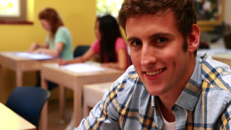 Handsome-student-smiling-to-camera-in-classroom