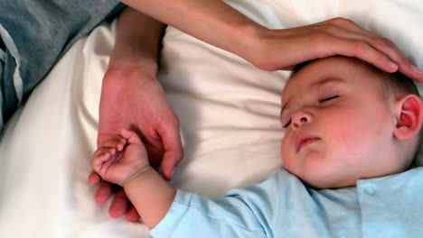 Mother-lying-with-sleeping-baby-boy-on-bed