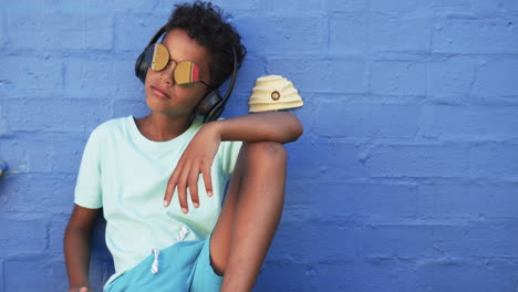 A-young-African-American-student-relaxes-against-a-blue-background-with-copy-space