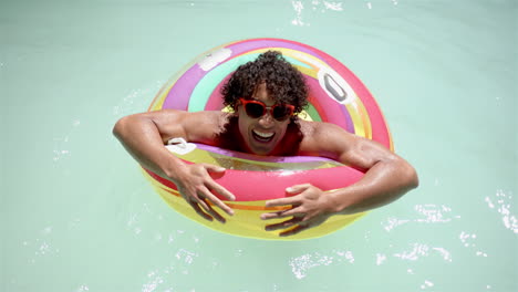Biracial-man-enjoys-pool-time-with-colorful-float-at-home