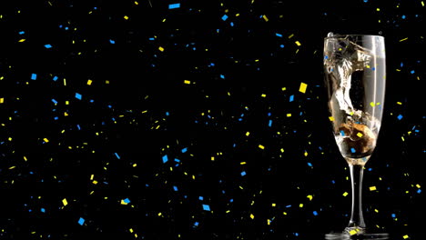 Animation-of-yellow-and-blue-confetti-falling-over-champagne-glass-on-black-background