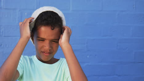 A-young-biracial-student-stands-against-blue-background,-copy-space