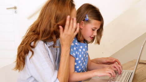 Little-girl-using-laptop-with-her-pretty-mother-at-the-table