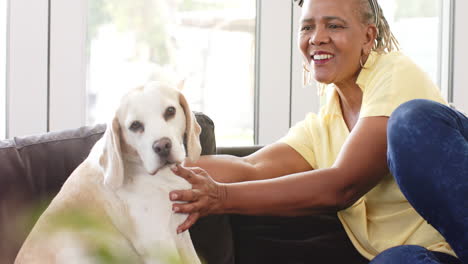 A-senior-African-American-woman-sitting-with-her-dog,-both-looking-relaxed