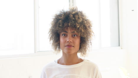Biracial-young-woman-with-curly-hair-standing,-looking-forward