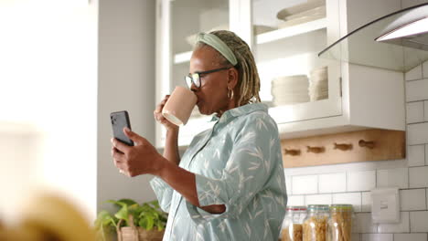Afroamerikanische-Seniorin-Hält-Smartphone-Und-Trinkt-Aus-Tasse