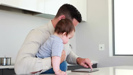 Vater-Hält-Sein-Baby-Vor-Der-Arbeit-Und-Benutzt-Tablet
