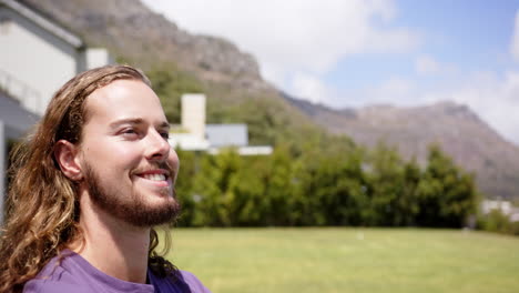 A-young-Caucasian-male-smiles-outdoors,-gazing-into-the-distance,-copy-space