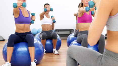 Fitness-class-sitting-on-exercise-balls-lifting-hand-weights
