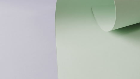 Nahaufnahme-Eines-Hellgrünen,-Aufgerollten-Stück-Papier-Auf-Blauem-Hintergrund-Mit-Kopierraum-In-Zeitlupe