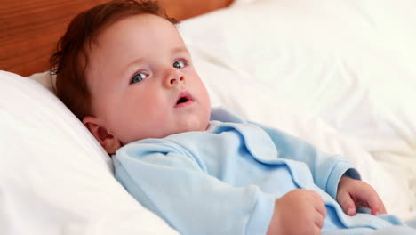 Baby-boy-in-blue-babygro-lying-on-bed