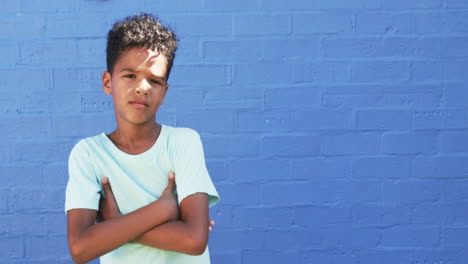 A-young-African-American-boy-stands-against-blue-background,-copy-space