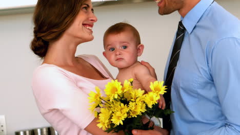 Madre-Sosteniendo-Al-Bebé-Con-Padre-Sosteniendo-Flores-Amarillas