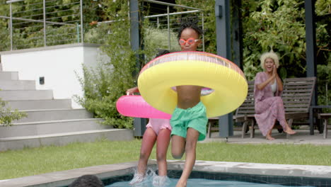 African-american-siblings-jumping-into-swimming-pool-to-father