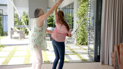 Asian-grandmother-with-grey-hair-is-dancing-with-biracial-granddaughter