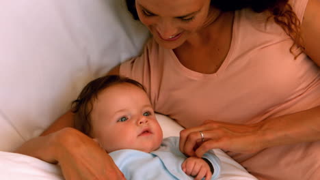 Mother-cuddling-her-baby-boy-on-bed