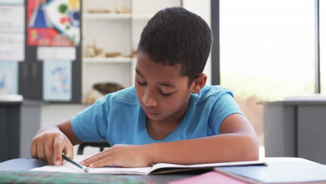 In-school,-a-young-African-American-student-focuses-on-his-notebook-in-the-classroom
