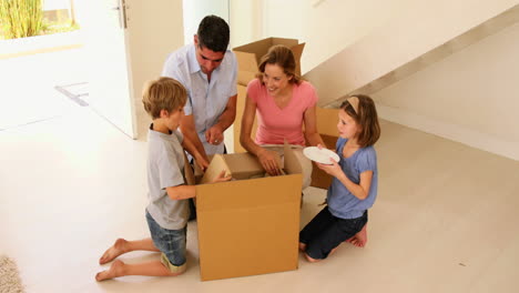 Glückliche-Familie-öffnet-Eine-Kiste-In-Ihrem-Neuen-Zuhause