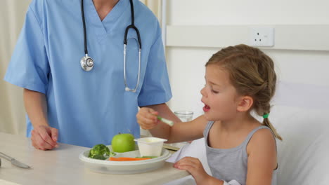 Nurse-feeding-sick-little-girl-in-bed