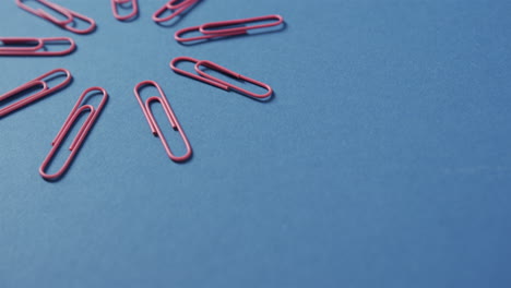 Red-paper-clips-are-scattered-on-a-blue-background